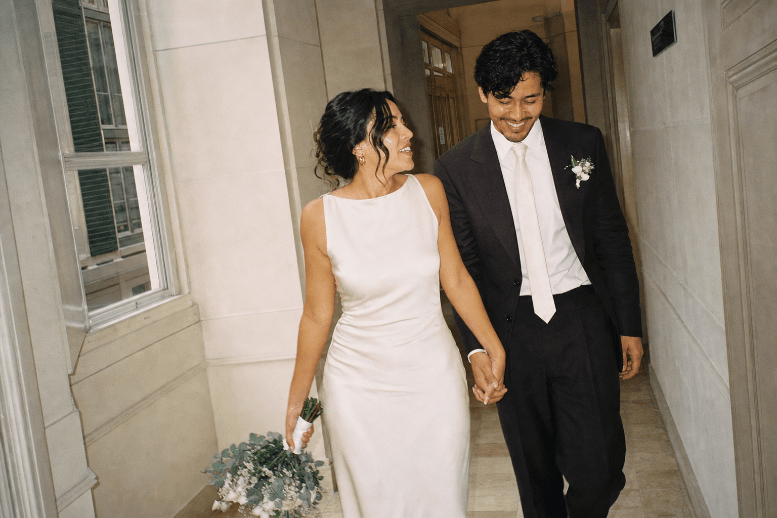 The newlyweds walking hand in hand between rooms