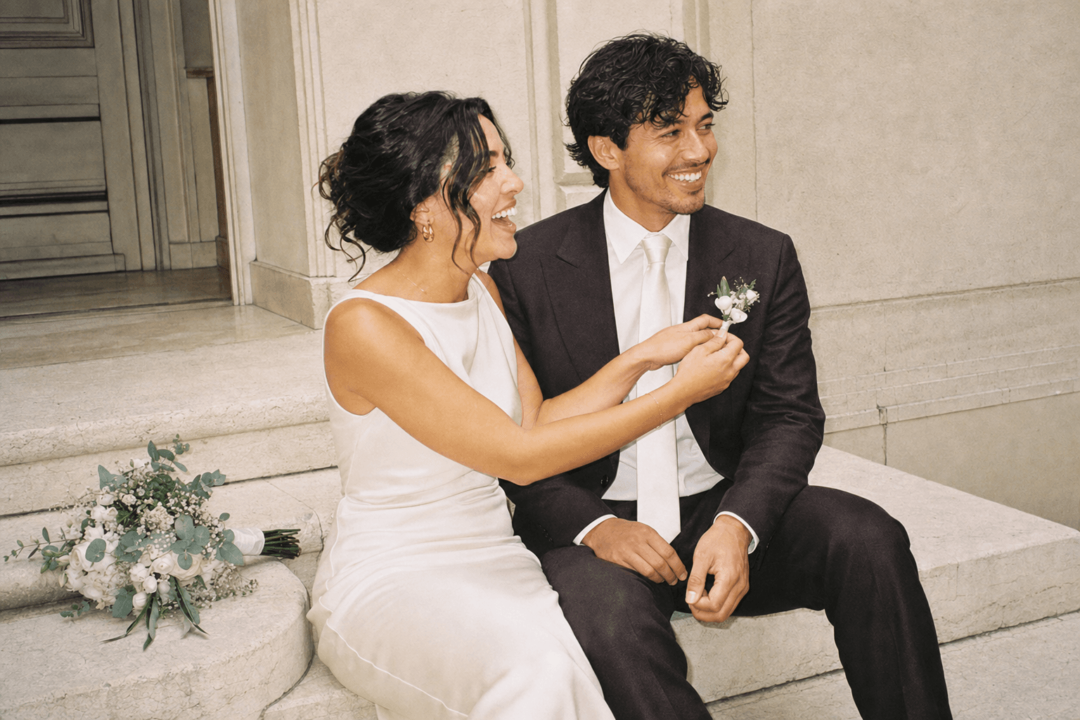 The bride fixing the groom's boutonniere on the steps