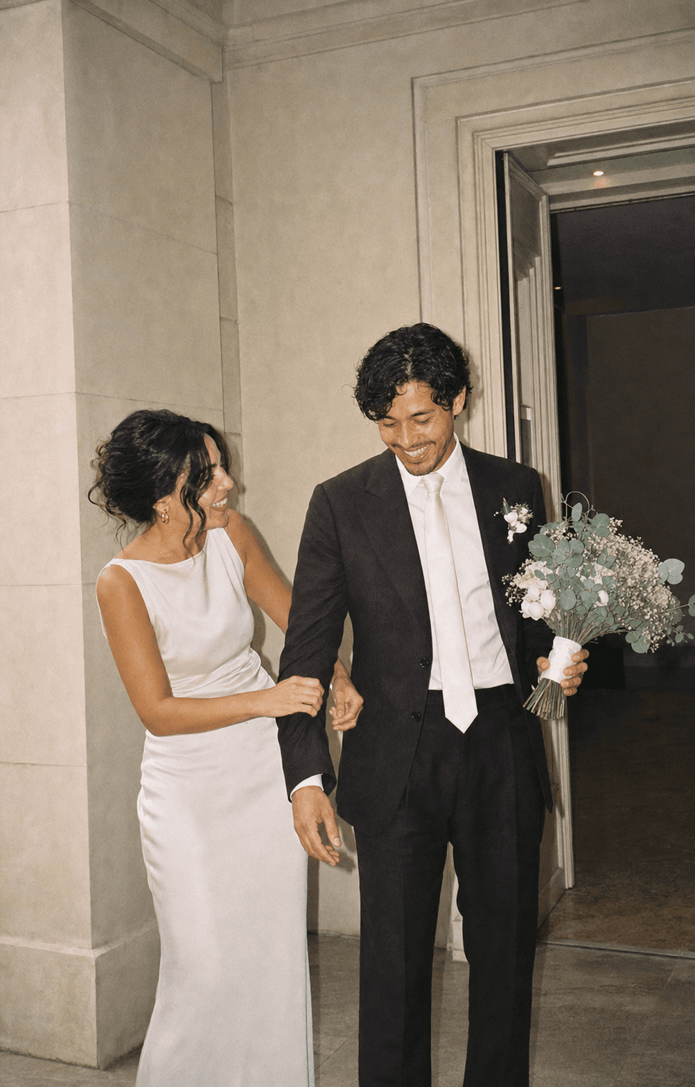 The groom holding the bouquet while the bride fixes his sleeve