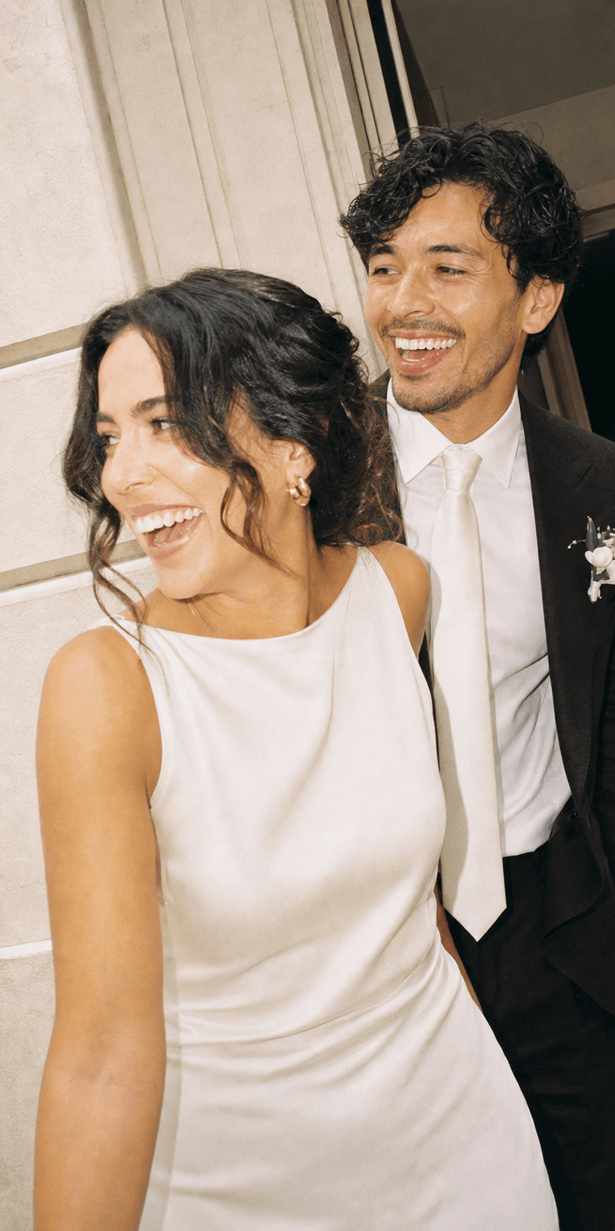 The newlyweds turning back laughing in the doorway